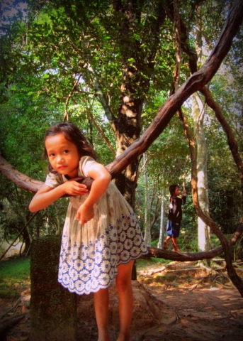 Little girl and her brother, swinging on vines near Ta Prohm, Cambodia